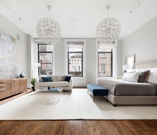 This master suite has a dressing room, a dreamy walk-in closet, and an extra-large ensuite bathroom. Two massive white pendants add textured, visual interest and soft lighting throughout.
