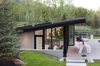 The roof has a large tongue-and-groove wood overhang that shades the pool deck and outdoor dining area.