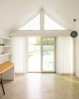 Official LLC installed a built-in desk and bed platform in Pool House. The high windows offer a glimpse out to the backyard, and curtains provide privacy when desired.