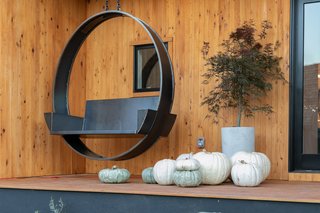 The black steel swing frames a dark window perfectly, lending a modern vibe to the wood exterior. Plants and white decorations break the colors up further.