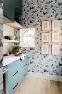 Swallow-printed wallpaper adds depth and pattern to the subdued kitchen color palette. 