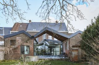 A Glass-Wrapped Living Space Cracks Open a Historic Brick Home in Belgium